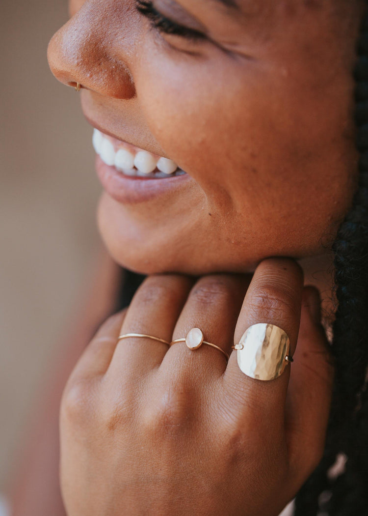 A gold ring stack with a 3 ring stack using a thin gold ring, a gemstone ring with a Rose Quartz stone, and the Supermoon Ring which is a hammered ring created to look like a moon ring by Hello Adorn.