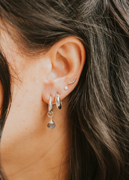 Close-up of an ear with multiple earrings against a blurred background