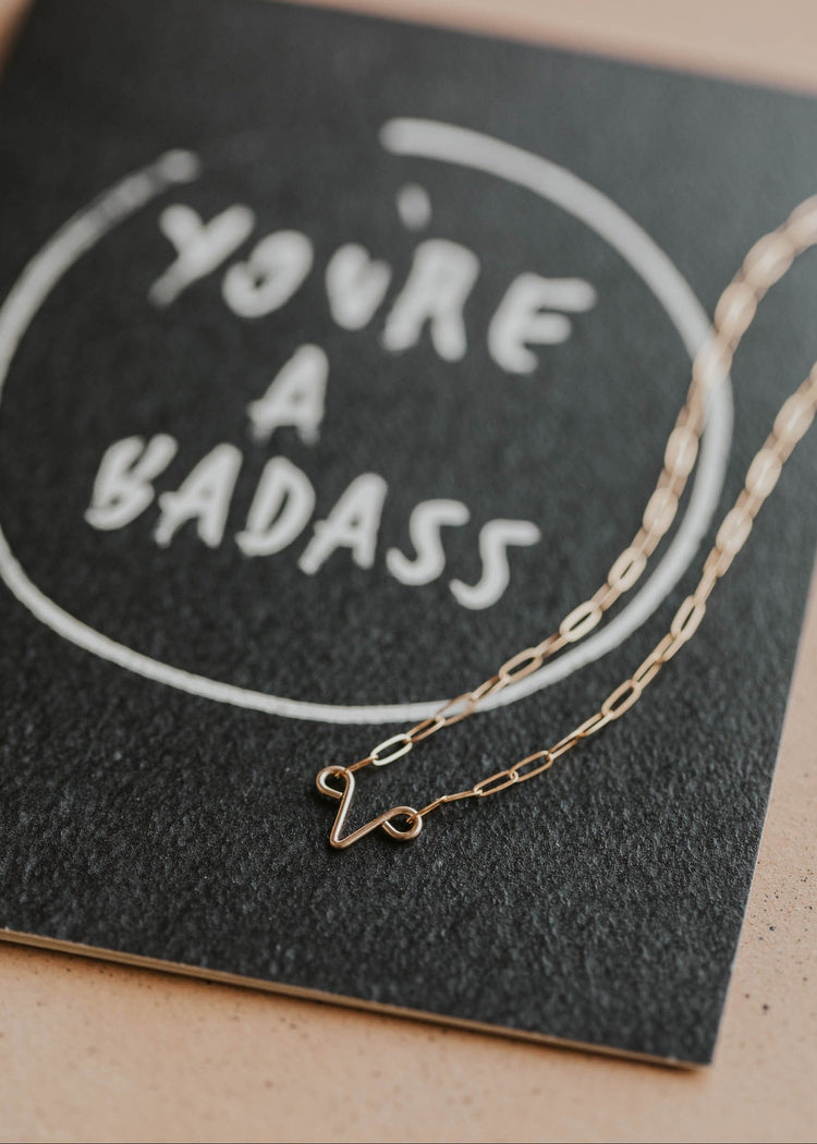 you're a badass card with uterus necklace flat lay