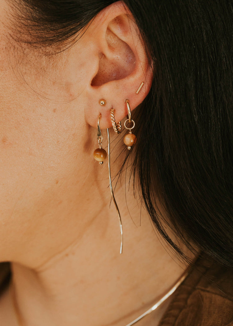 Close-up of an ear with gold earrings against a dark background