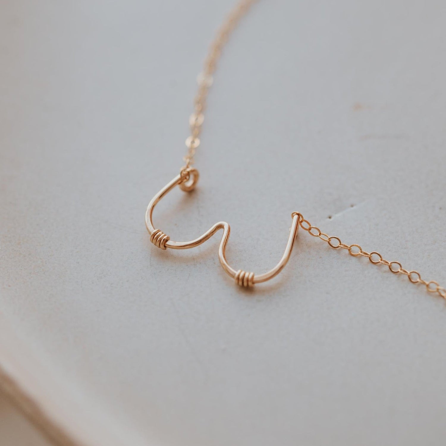 Gold necklace with a unique design on a light background