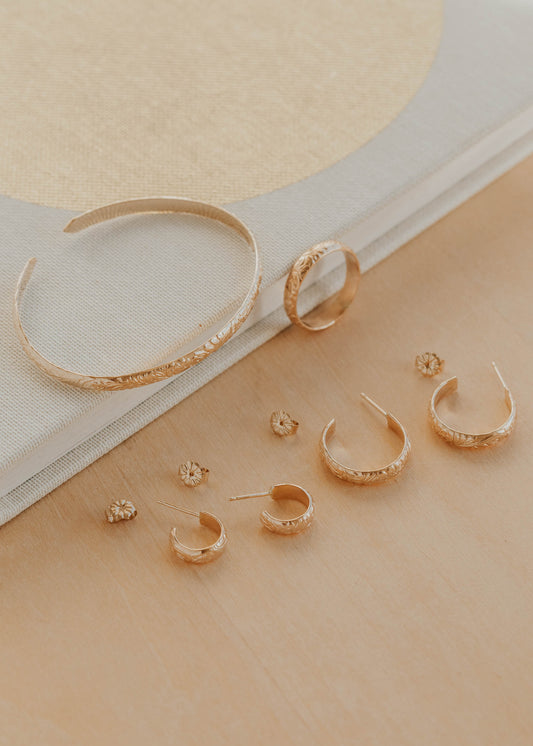 Set of gold hoop earrings on a beige surface with a white cloth