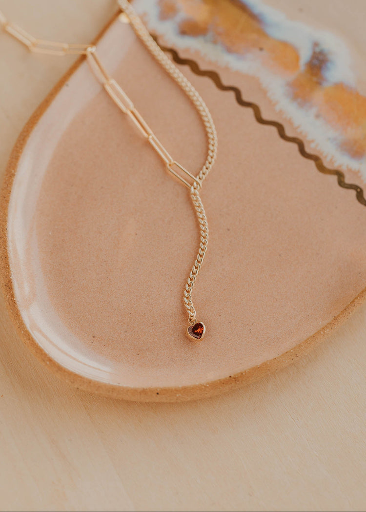 Gold necklace on a textured beige surface