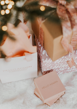 Hello Adorn wrapped gifts under a tree.