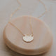 A necklace with a circle pendant to create the Supermoon Necklace handmade by Hello Adorn using a gold disc necklace with a dainty chain necklace to create this moon statement necklace.