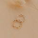 Two gold rings on a beige surface with dried grass.
