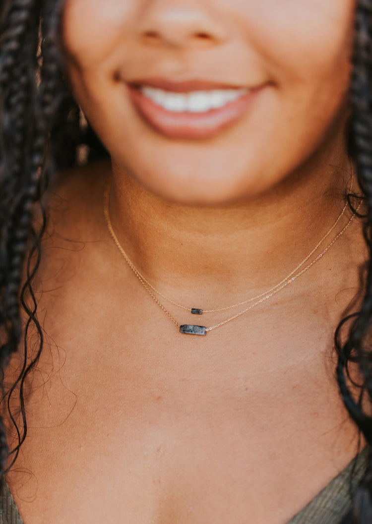 A necklace layering idea using multiple gemstone necklaces shown from the Gemma Collection at Hello Adorn,  both of these are black stone necklaces shown attached to a gold chain necklace.