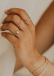 Close-up of a hand wearing gold rings and a bracelet on a blurred background