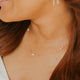 Close-up of a woman wearing gold earrings and a necklace with a blurred background