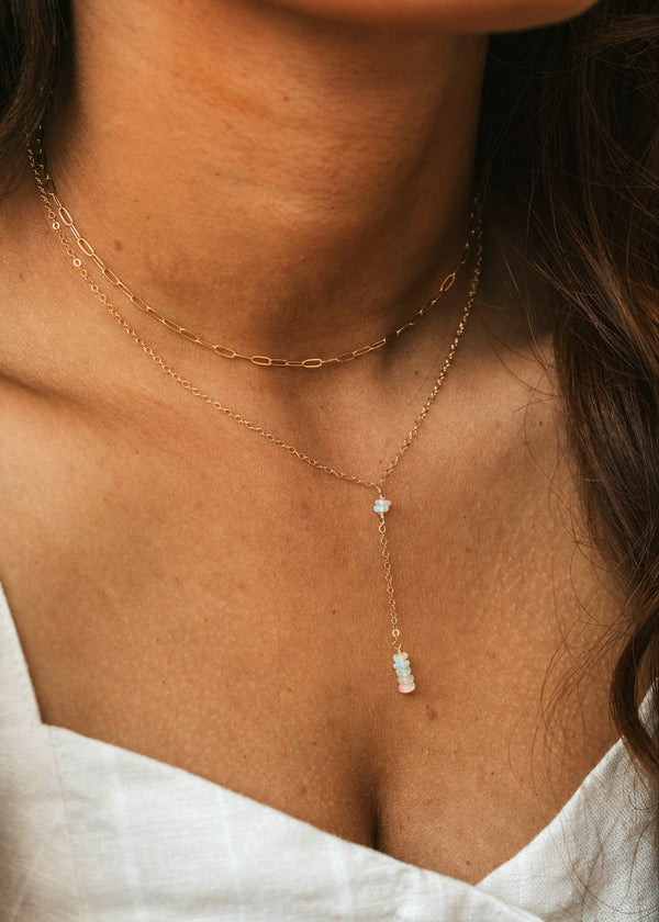 Close-up of a person wearing a delicate gold necklace with small stones.
