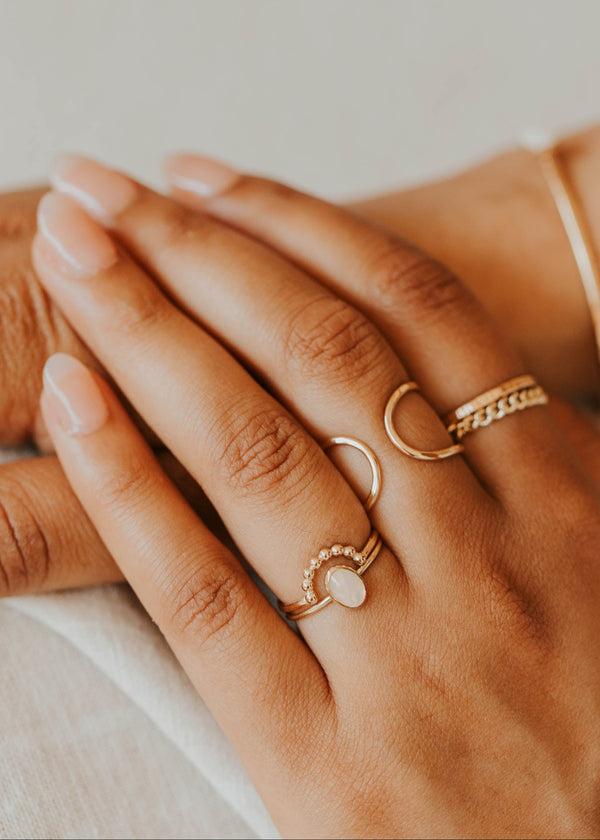 Close-up of hands wearing gold rings on a neutral background