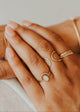 Close-up of hands wearing gold rings on a neutral background