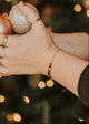 Hand holding two Christmas ornaments with a blurred Christmas tree in the background