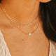 Close-up of a person wearing gold necklaces with a heart pendant.