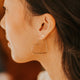Close-up of a person wearing a heart-shaped earring with a blurred background