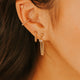 Close-up of a person wearing gold earrings with a blurred background