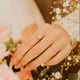 Hand with a heart-shaped ring holding flowers with a blurred background