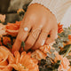 Person arranging a bouquet of orange flowers with greenery.