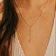 Gold necklace worn by a person with a blurred background
