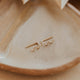 Gold earrings on a ceramic dish with a blurred background