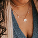 Close-up image of a stylish charm necklace featuring delicate charms and a shiny chain, perfect for adding a personalized touch to any outfit.