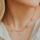 Close-up image of a stylish charm necklace featuring delicate charms and a shiny chain, perfect for adding a personalized touch to any outfit.