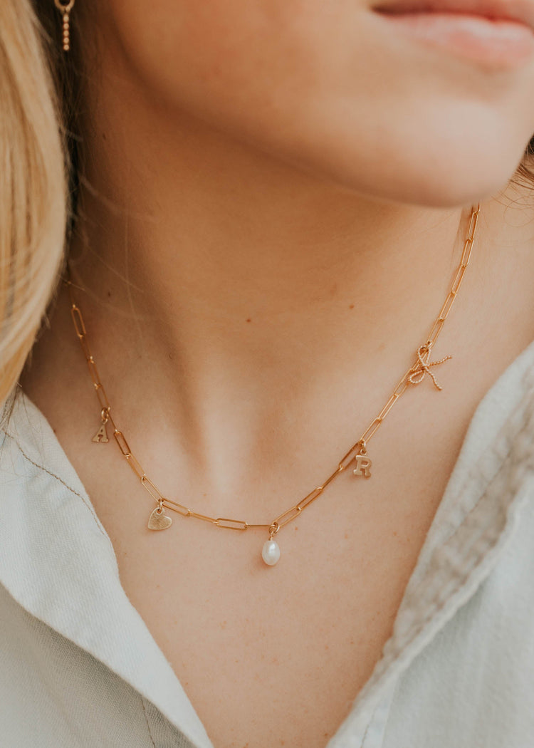 Close-up image of a stylish charm necklace featuring delicate charms and a shiny chain, perfect for adding a personalized touch to any outfit.