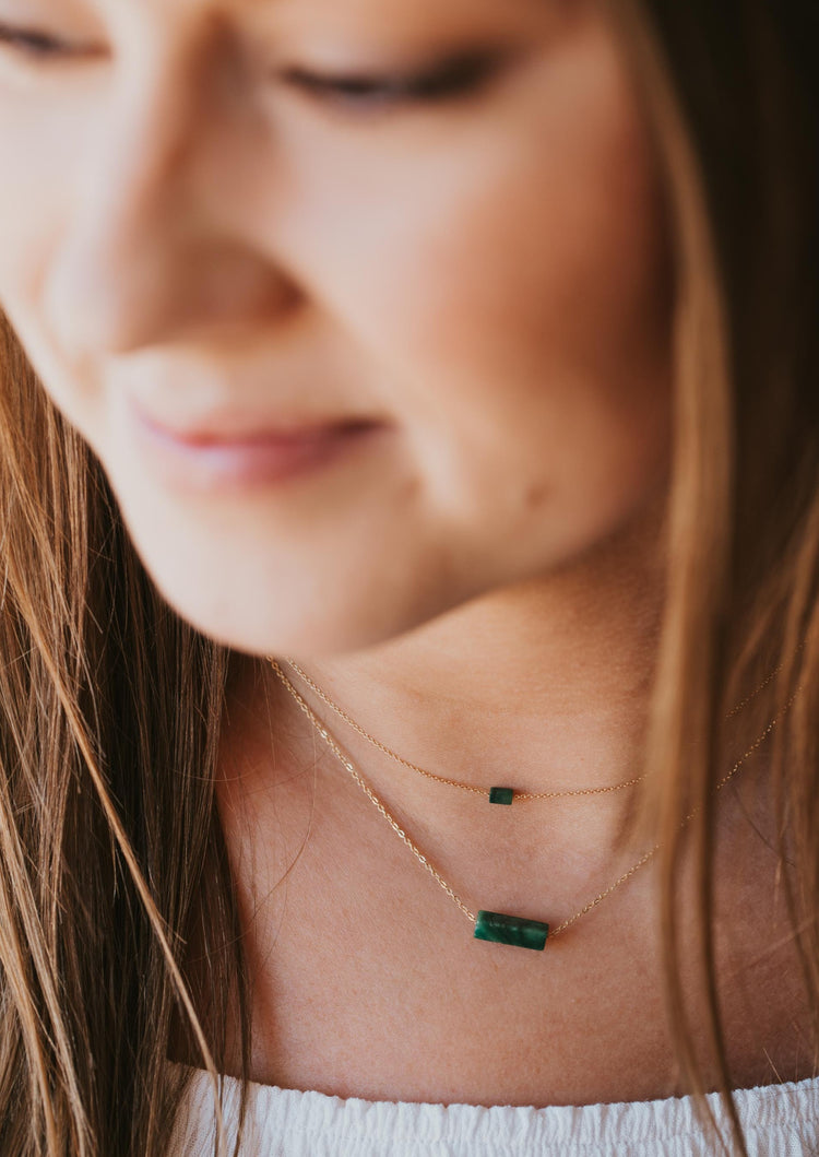 A model wearing multiple gemstone necklaces from Hello Adorn's Gemma Collection, these are green stone necklaces which are shown in 14k gold fill.