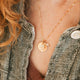 Person wearing a gold Hello Adorn Mental Health necklace with circular pendants and meaning charms