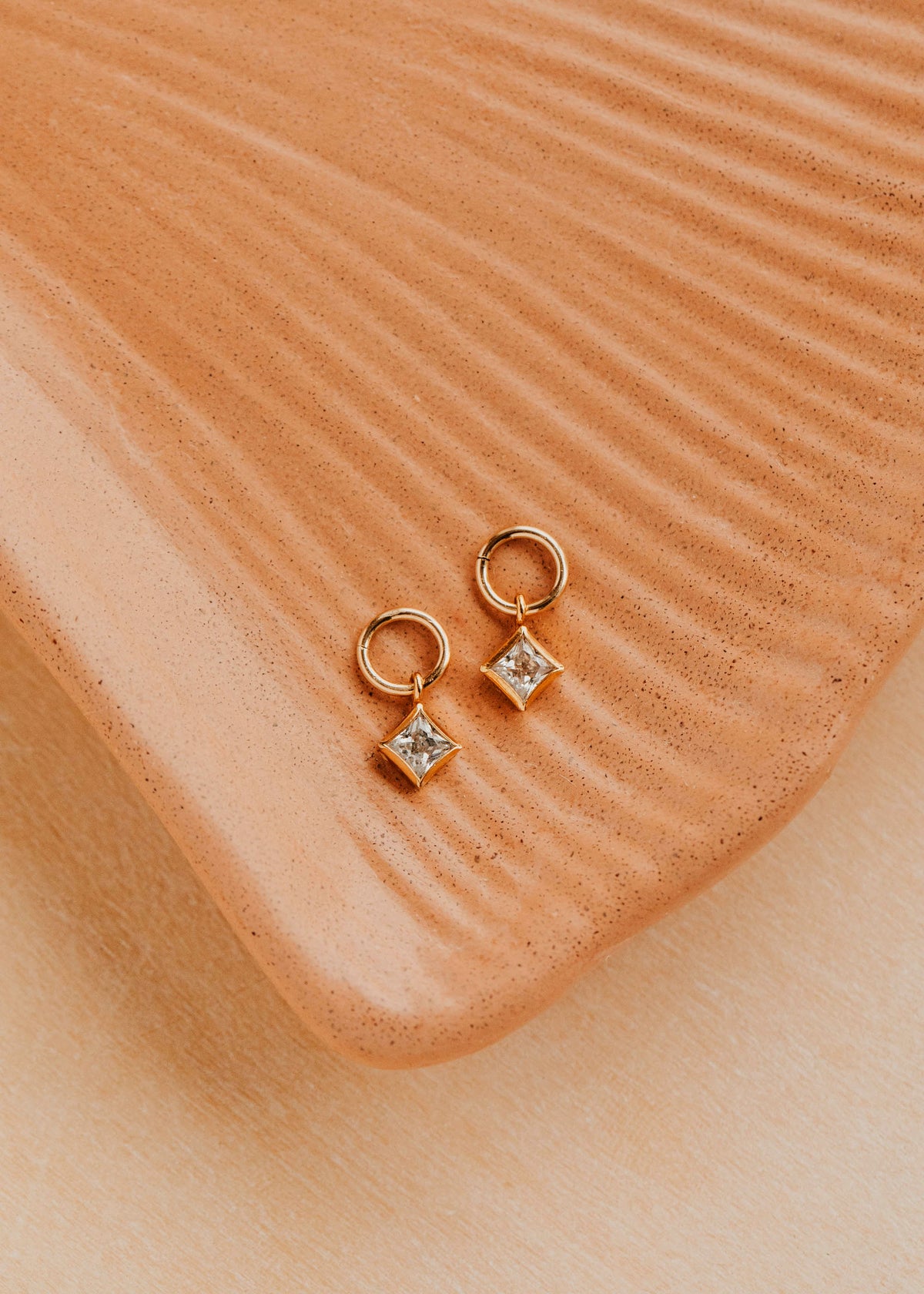 14K Gold Fill Grace Charms by Hello Adorn - pair of CZ star charms on gold huggies on ceramic dish