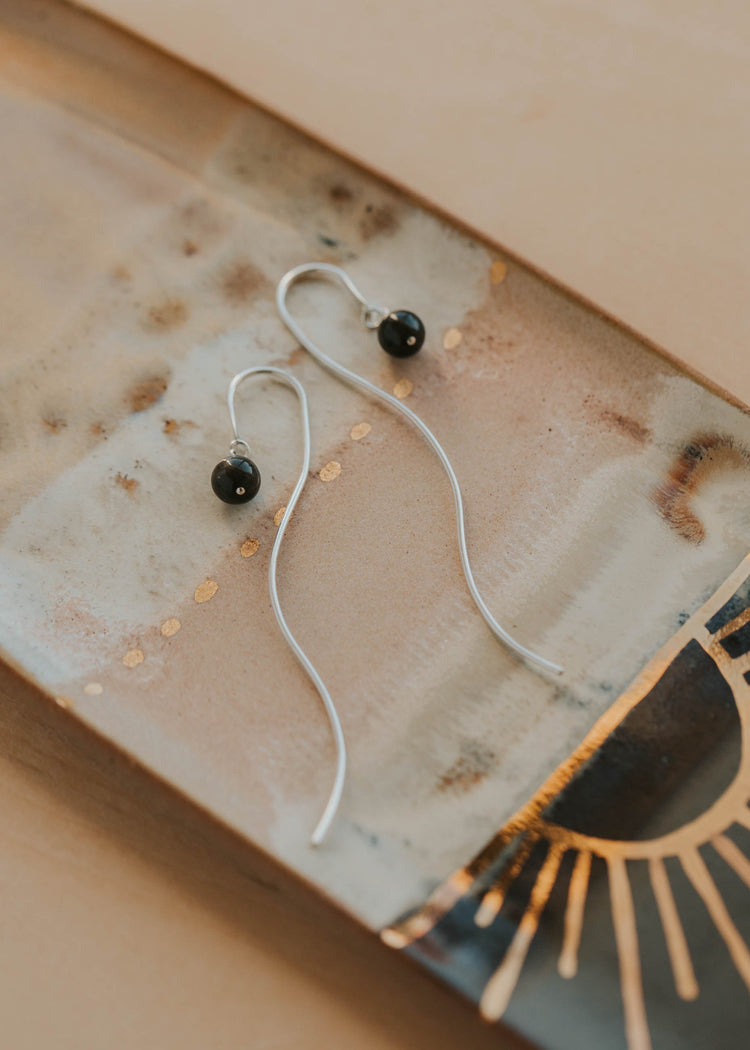 Silver earrings with black stones on a textured surface