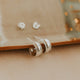 Pair of silver earrings on a beige surface with a blurred background