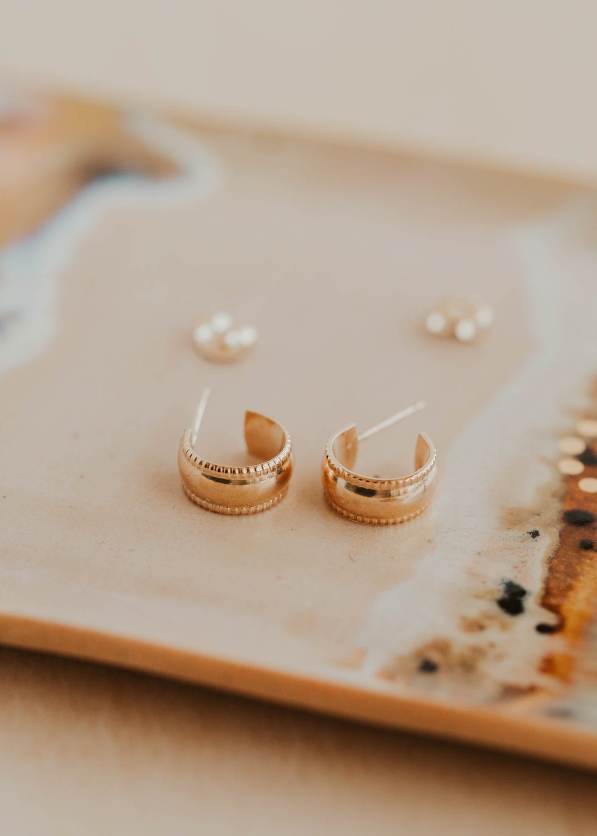 Gold hoop earrings on a decorative plate with a blurred background