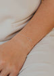 Silver bracelet on a wrist with a neutral background