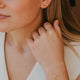 Woman wearing gold earrings and bracelet, close-up of face and hand