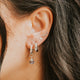 Close-up of an ear with multiple earrings against a blurred background