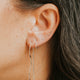 Close-up of an ear with multiple earrings against a blurred background