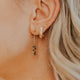 Close-up of an ear with gold earrings and a blurred background