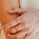 Close-up of a hand with gold rings and bracelet on a neutral background