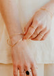 Close-up of hands wearing gold bracelets and rings on a neutral background