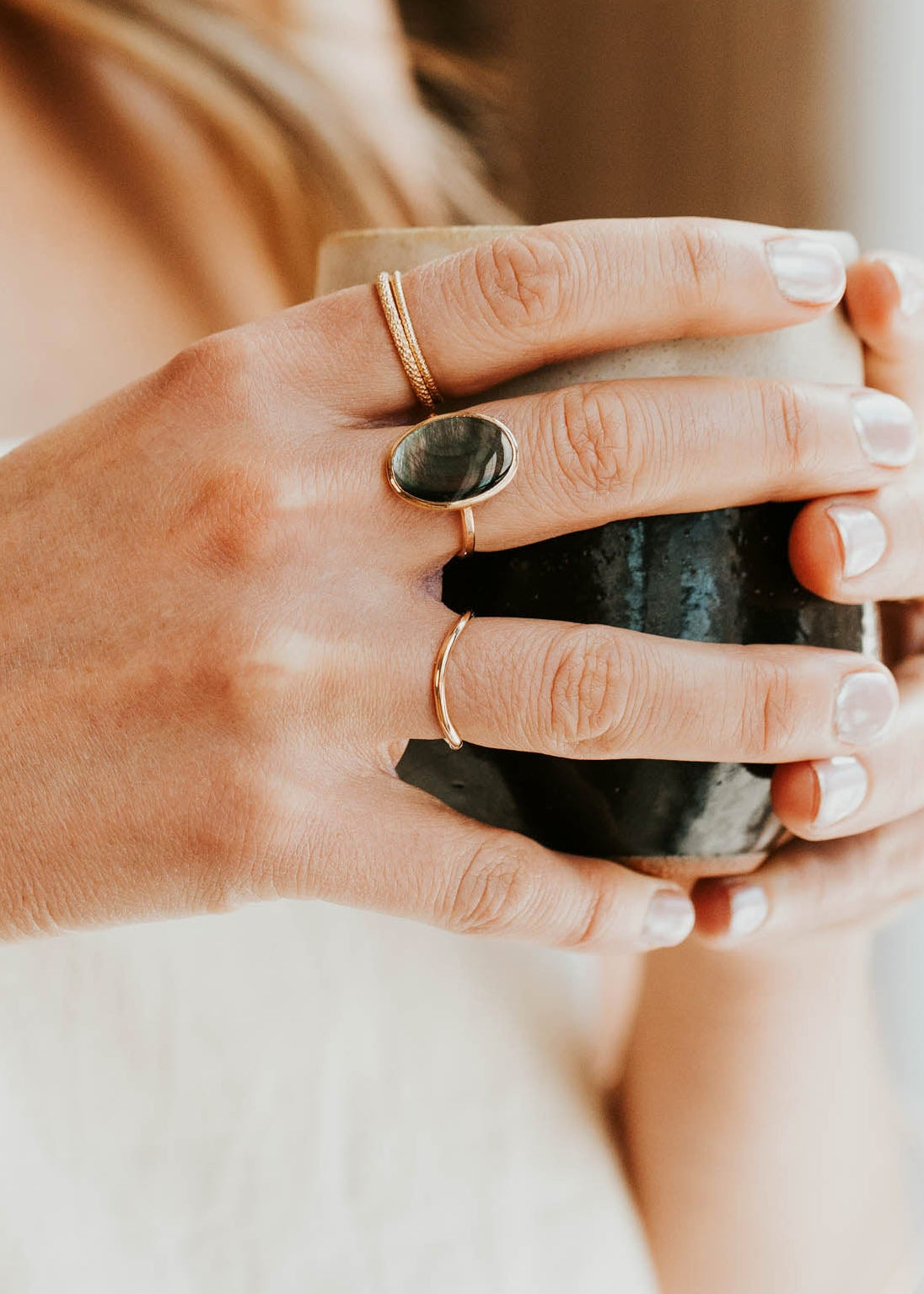 Person holding a black mug with a blurred background