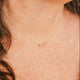 Close-up of a person wearing a delicate gold necklace with small beads.