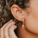 14k gold fill tiny twist earrings in second lobe styled with Bold Hoops and a crystal hoop charm