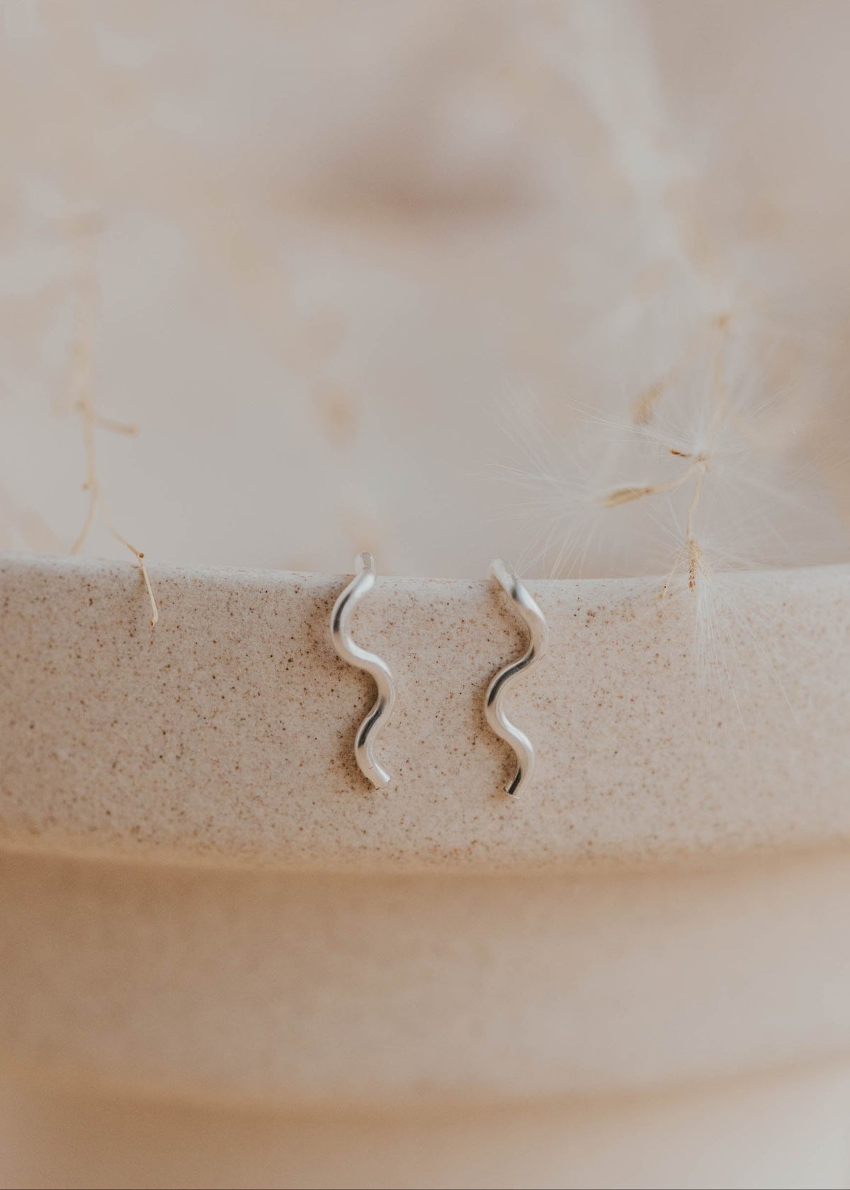Sterling silver Tiny Wave Ear Climber earrings by Hello Adorn on a ceramic dish
