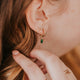 model styling tiny twist earrings with hoops and charms