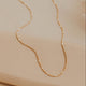 Gold necklace on a beige surface