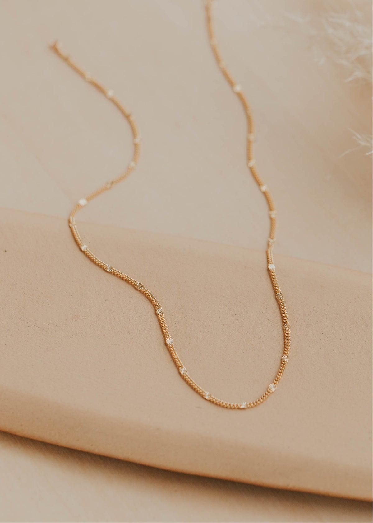 Gold necklace on a beige surface