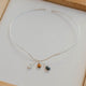 Silver necklace with three small colored stones in a wooden frame