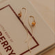 Gold earrings with a small round bead on a book