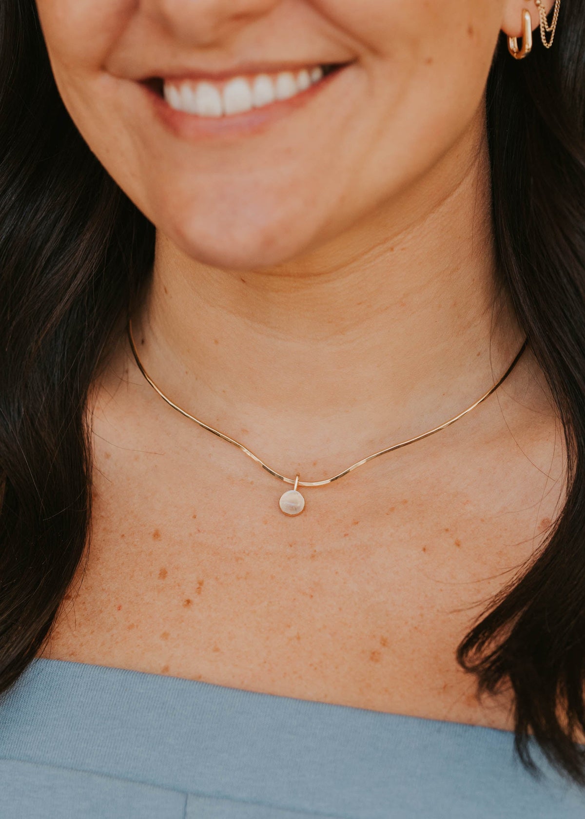 Close-up of a person wearing a delicate gold necklace with a small pendant.